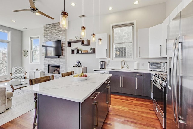 kitchen with appliances with stainless steel finishes, open floor plan, a fireplace, and a breakfast bar