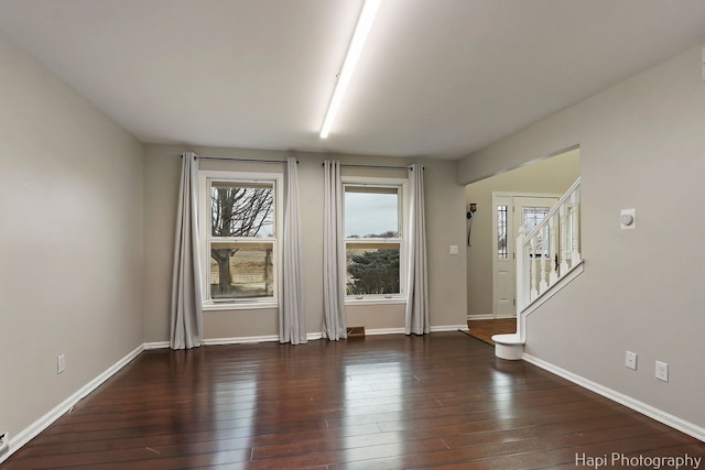 unfurnished room with stairway, wood-type flooring, and baseboards