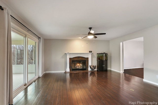 unfurnished living room with wood-type flooring, baseboards, a ceiling fan, and a glass covered fireplace