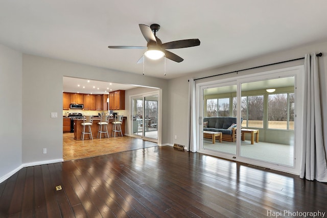 unfurnished living room with baseboards, ceiling fan, visible vents, and hardwood / wood-style floors