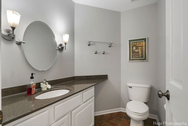 half bathroom featuring tile patterned flooring, baseboards, vanity, and toilet