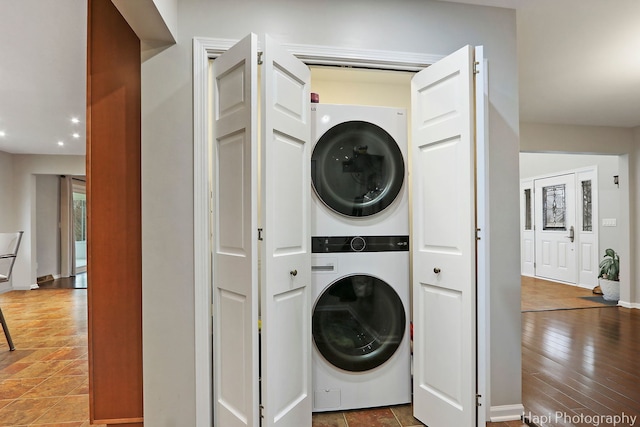 washroom with recessed lighting, stacked washing maching and dryer, wood finished floors, laundry area, and baseboards