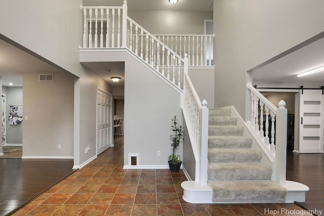 stairway with a high ceiling, visible vents, baseboards, and a barn door