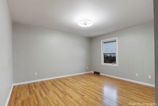 empty room featuring baseboards, visible vents, and light wood-style floors