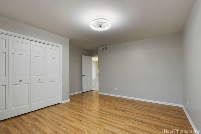 unfurnished bedroom featuring light wood-style flooring, a closet, visible vents, and baseboards