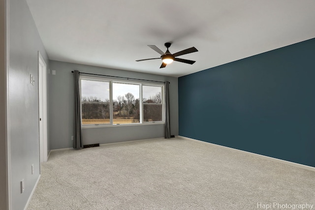 carpeted spare room with ceiling fan and baseboards