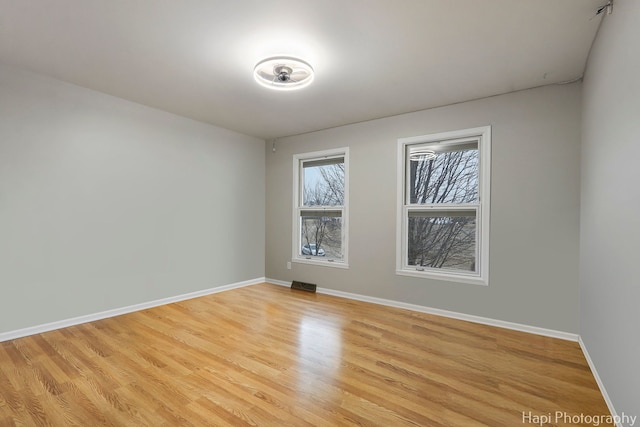 empty room featuring light wood-style floors, visible vents, and baseboards