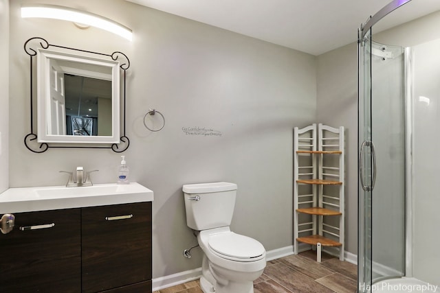 bathroom with baseboards, toilet, wood tiled floor, an enclosed shower, and vanity