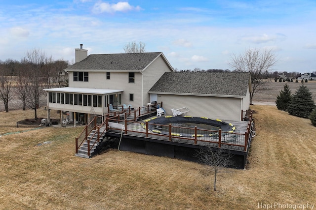 rear view of property featuring a lawn, a sunroom, a chimney, stairway, and a deck