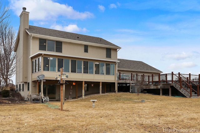 back of house with a sunroom, a chimney, stairway, roof with shingles, and a wooden deck