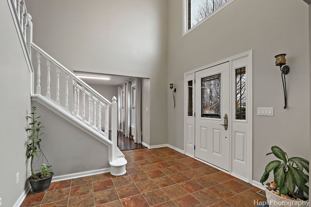 foyer entrance with stairway, a towering ceiling, and baseboards