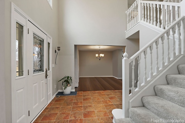 entrance foyer with stairs, a high ceiling, a chandelier, and baseboards