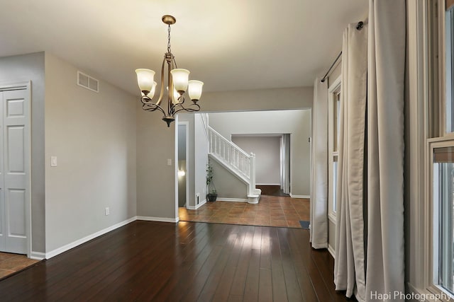 unfurnished dining area with visible vents, dark wood finished floors, baseboards, and stairs