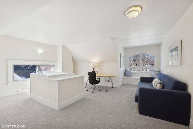 carpeted home office with vaulted ceiling and baseboards