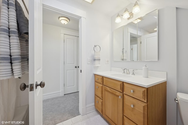 bathroom featuring toilet, baseboards, and vanity