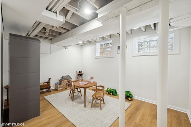 below grade area featuring light wood-type flooring, a healthy amount of sunlight, and baseboards