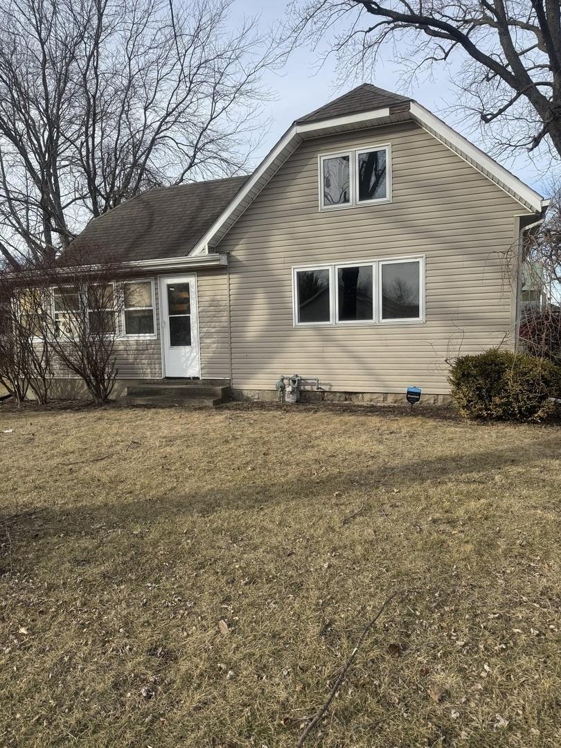 exterior space with a shingled roof and a yard