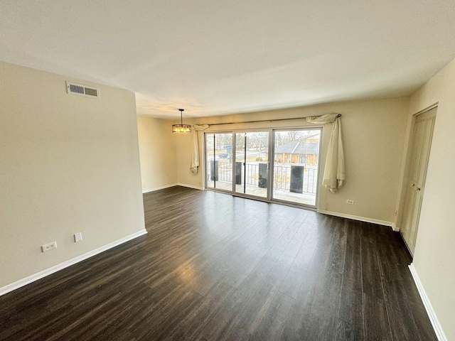 spare room with dark wood-style floors, visible vents, and baseboards