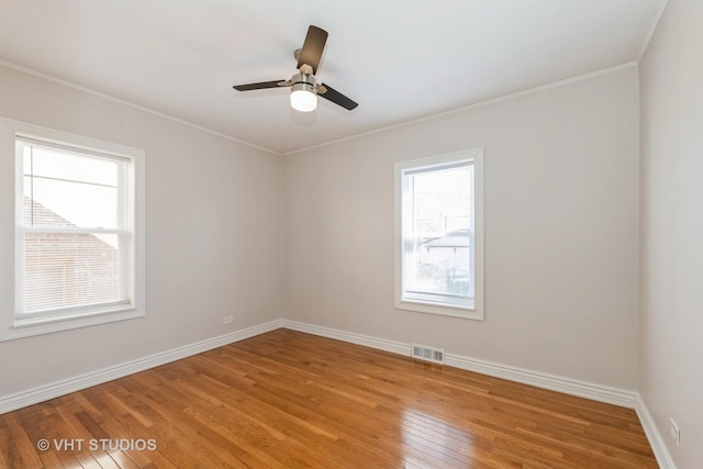 spare room with visible vents, baseboards, a ceiling fan, light wood-style flooring, and crown molding