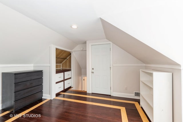 bonus room featuring baseboards, visible vents, vaulted ceiling, and wood finished floors