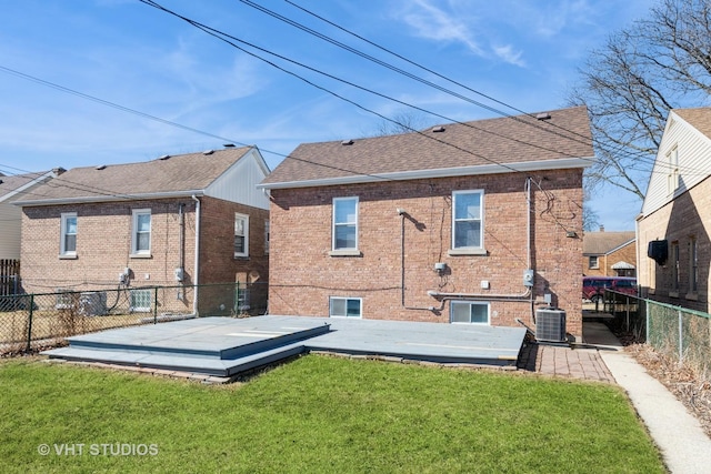 rear view of property with a fenced backyard, central AC, brick siding, a shingled roof, and a yard