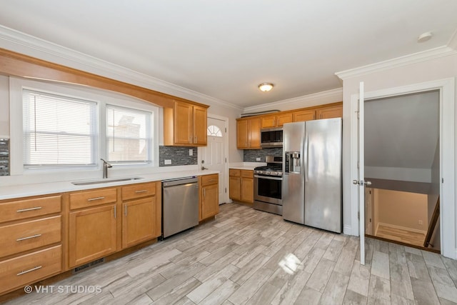 kitchen featuring stainless steel appliances, a sink, light countertops, light wood-type flooring, and decorative backsplash