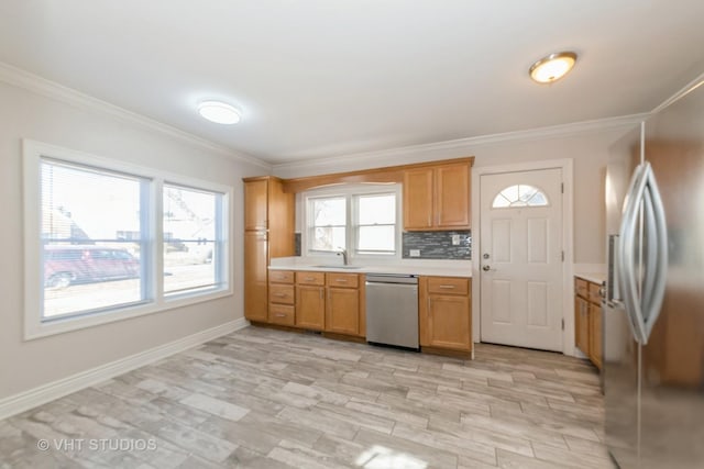 kitchen with stainless steel appliances, a sink, light countertops, ornamental molding, and backsplash