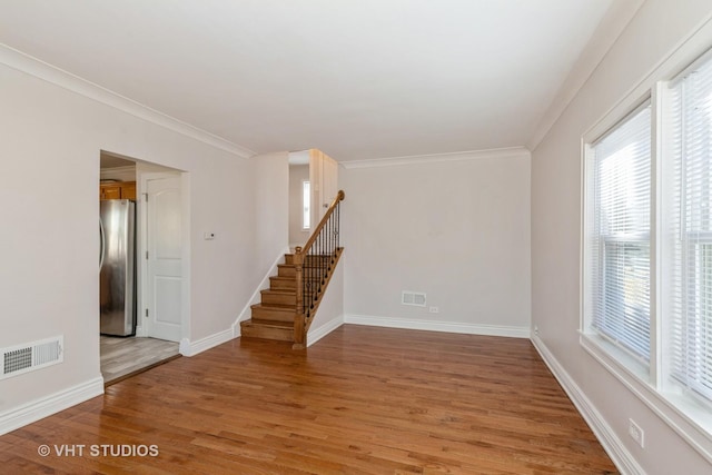 spare room featuring light wood-type flooring, visible vents, stairway, and baseboards