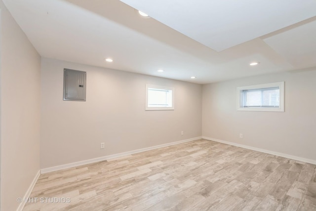 below grade area featuring recessed lighting, electric panel, light wood-style flooring, and baseboards