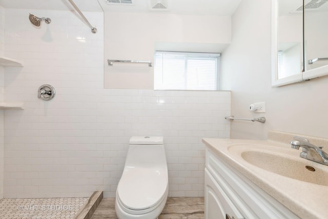 full bathroom featuring toilet, visible vents, a tile shower, and vanity