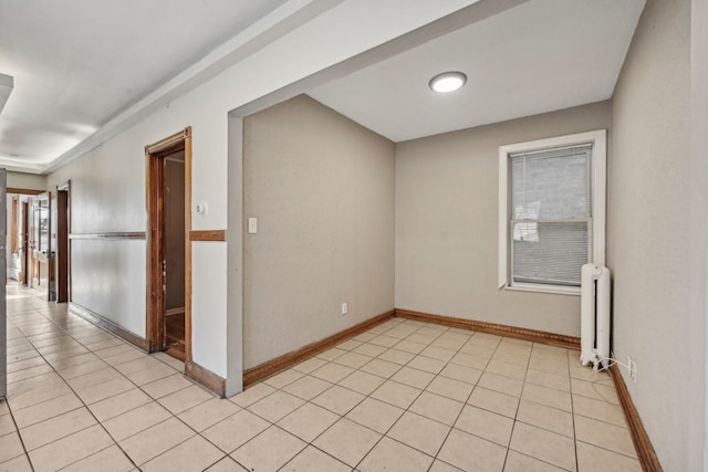 unfurnished room with radiator, light tile patterned flooring, and baseboards