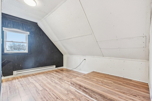 additional living space with a baseboard radiator, lofted ceiling, and wood finished floors