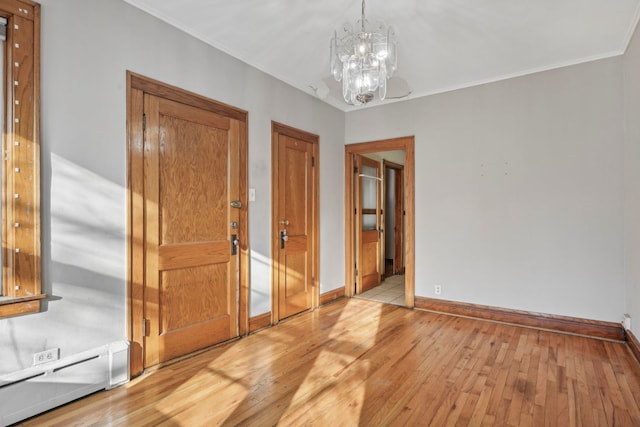 unfurnished room with light wood finished floors, baseboards, ornamental molding, and a notable chandelier