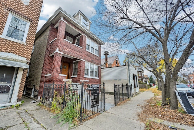 view of side of property featuring a fenced front yard, a gate, and brick siding