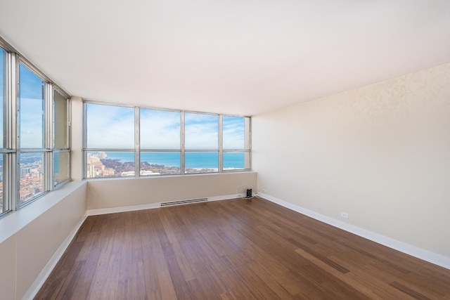 spare room with dark wood-style floors, a water view, and baseboards