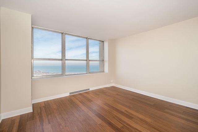 empty room featuring visible vents, a water view, baseboards, and wood finished floors