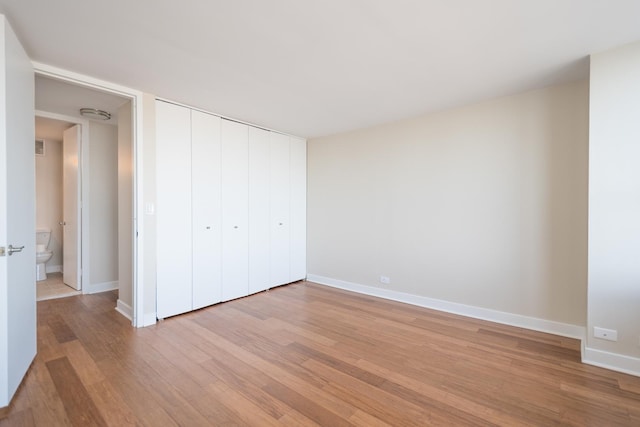 unfurnished bedroom featuring light wood-type flooring, a closet, and baseboards