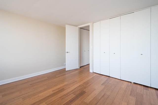 unfurnished bedroom featuring a closet, baseboards, and light wood finished floors