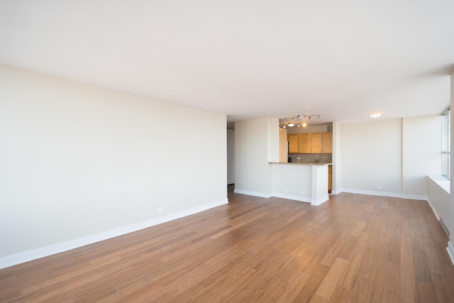 unfurnished living room featuring light wood-type flooring and baseboards