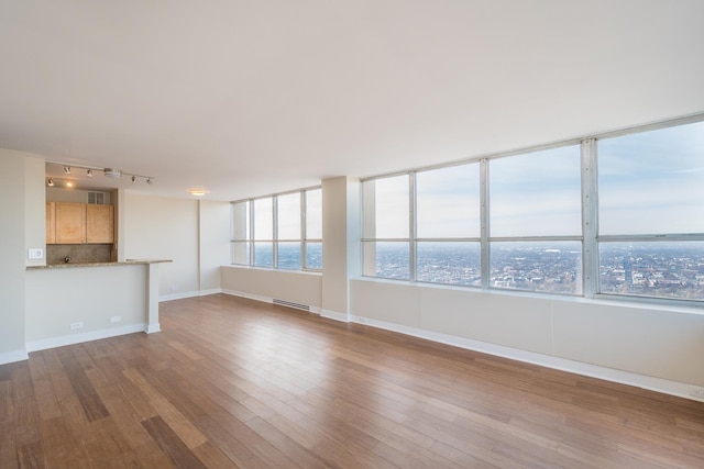 unfurnished living room featuring baseboards, wood finished floors, and a healthy amount of sunlight