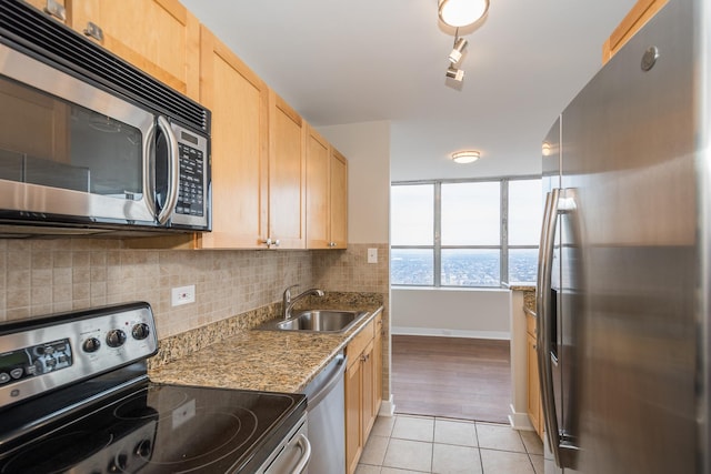 kitchen with light tile patterned flooring, a sink, appliances with stainless steel finishes, backsplash, and light brown cabinetry