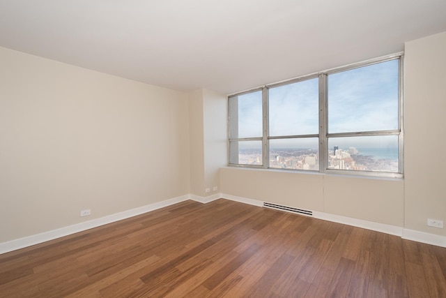 spare room featuring visible vents, plenty of natural light, baseboards, and wood finished floors
