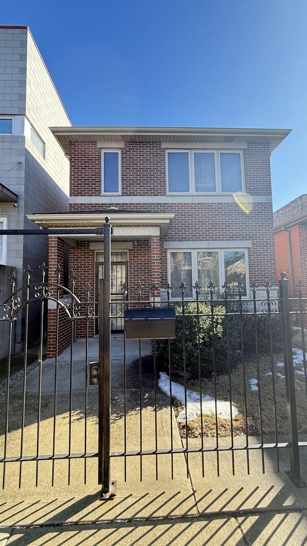 view of front of property featuring a gate, fence, and brick siding