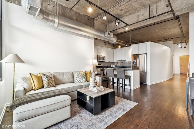 living room featuring rail lighting, visible vents, dark wood finished floors, and a towering ceiling