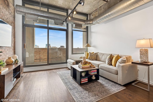 living area with hardwood / wood-style floors, rail lighting, and a high ceiling