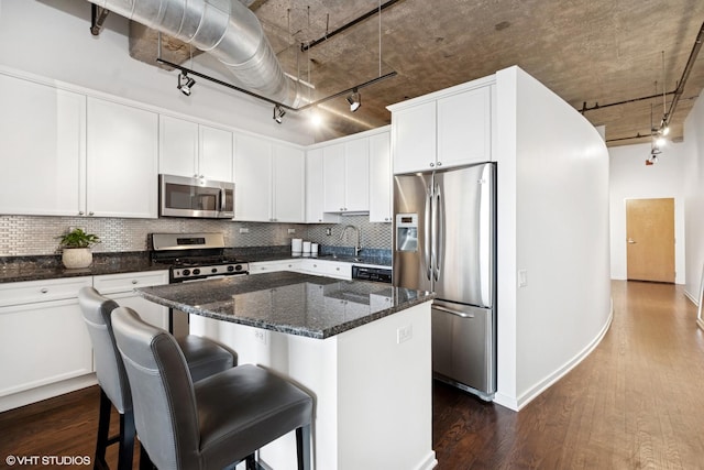 kitchen featuring dark wood-style floors, stainless steel appliances, tasteful backsplash, and a kitchen island