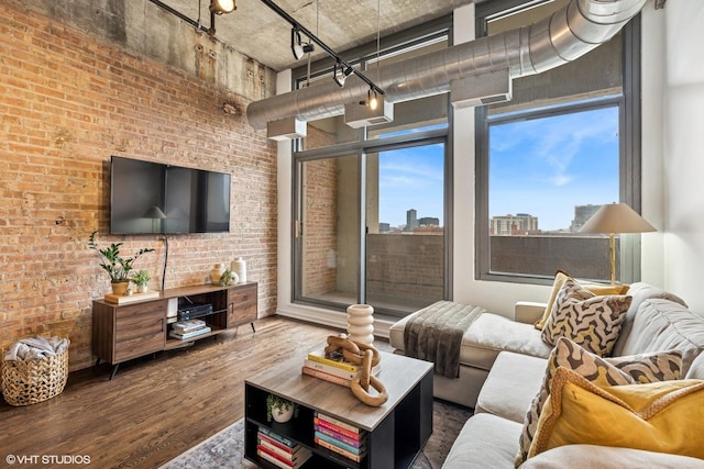 living room featuring brick wall, wood finished floors, and a towering ceiling