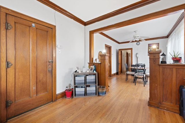 foyer featuring baseboards, ceiling fan, light wood-style flooring, and crown molding