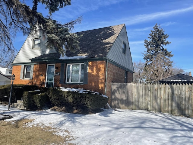 view of front of property featuring a garage, fence, and brick siding