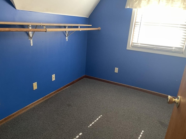 spare room featuring vaulted ceiling, carpet flooring, and baseboards